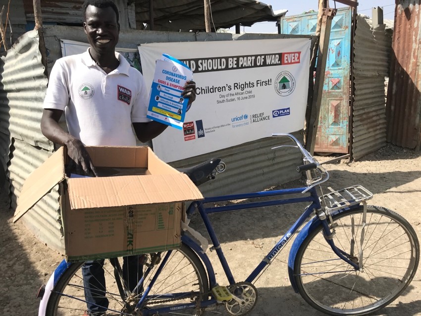 A person with a bicycle in front of a box

Description automatically generated